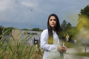 Marym Musab stands outdoors in a white lab coat