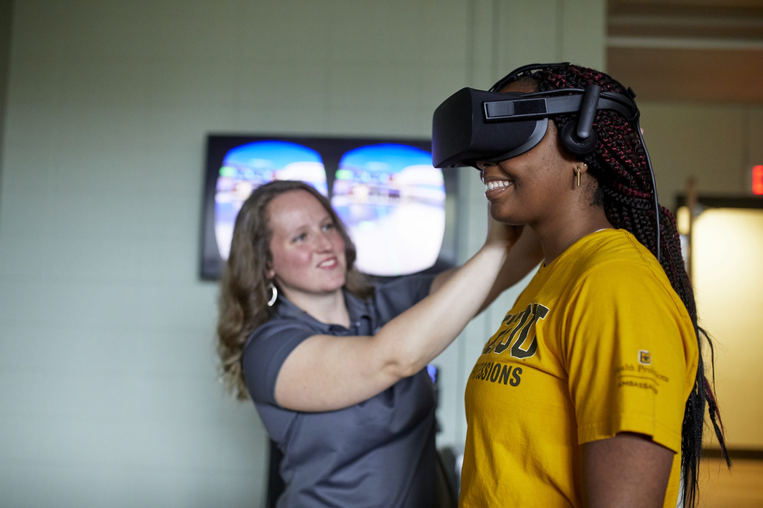 Faculty member adjusts VR goggles on a research participant