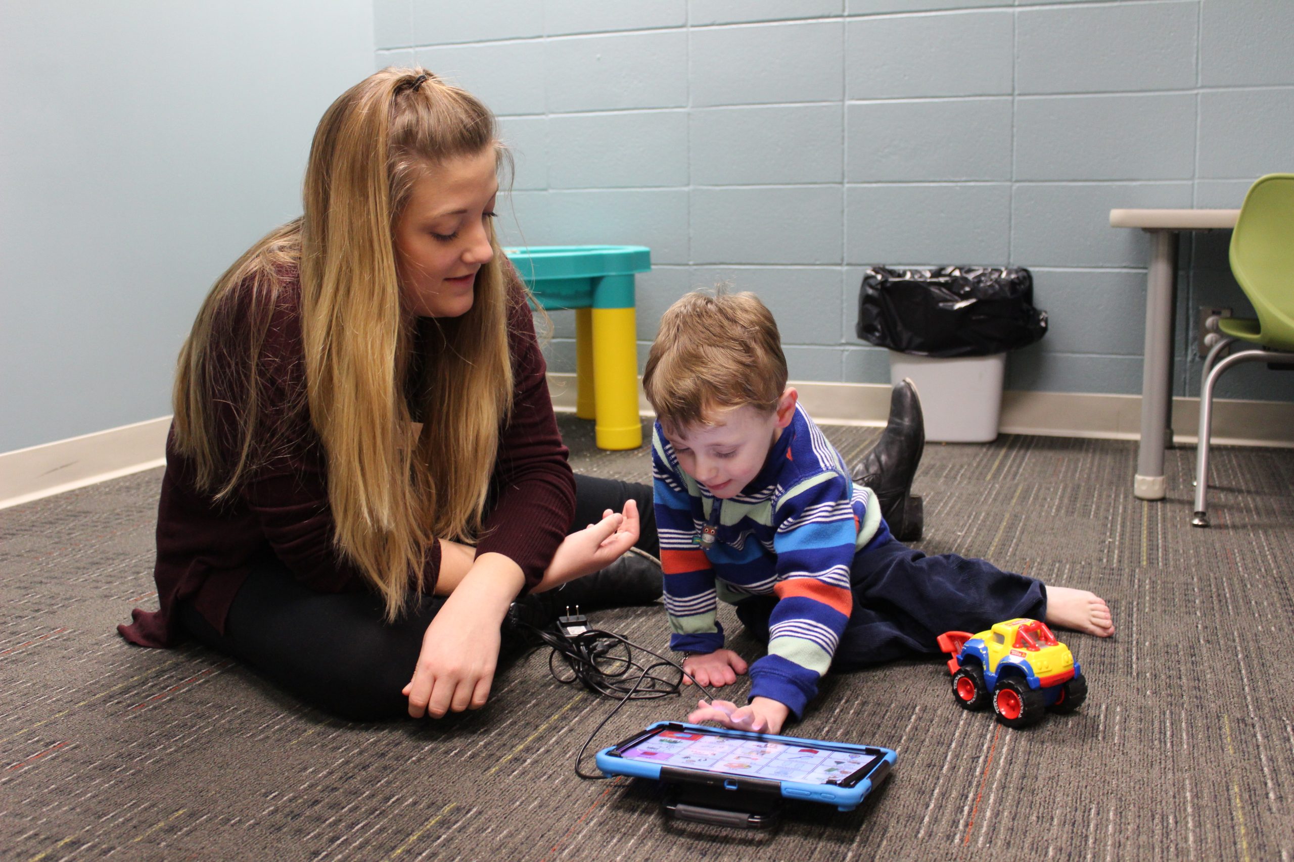 Girl shows child how to use an iPad with assistive technology